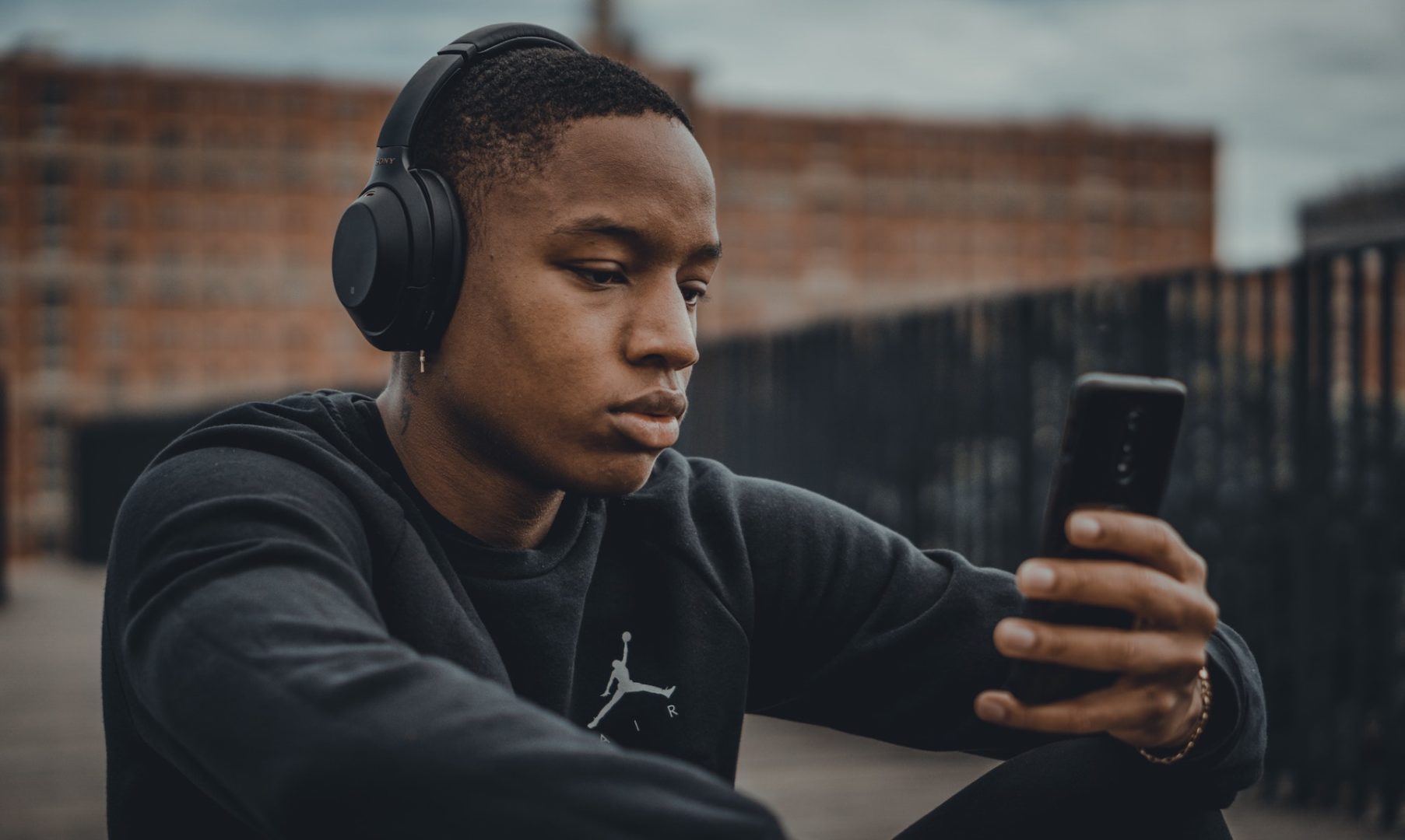 Boy listens to headphones while staring at phone.