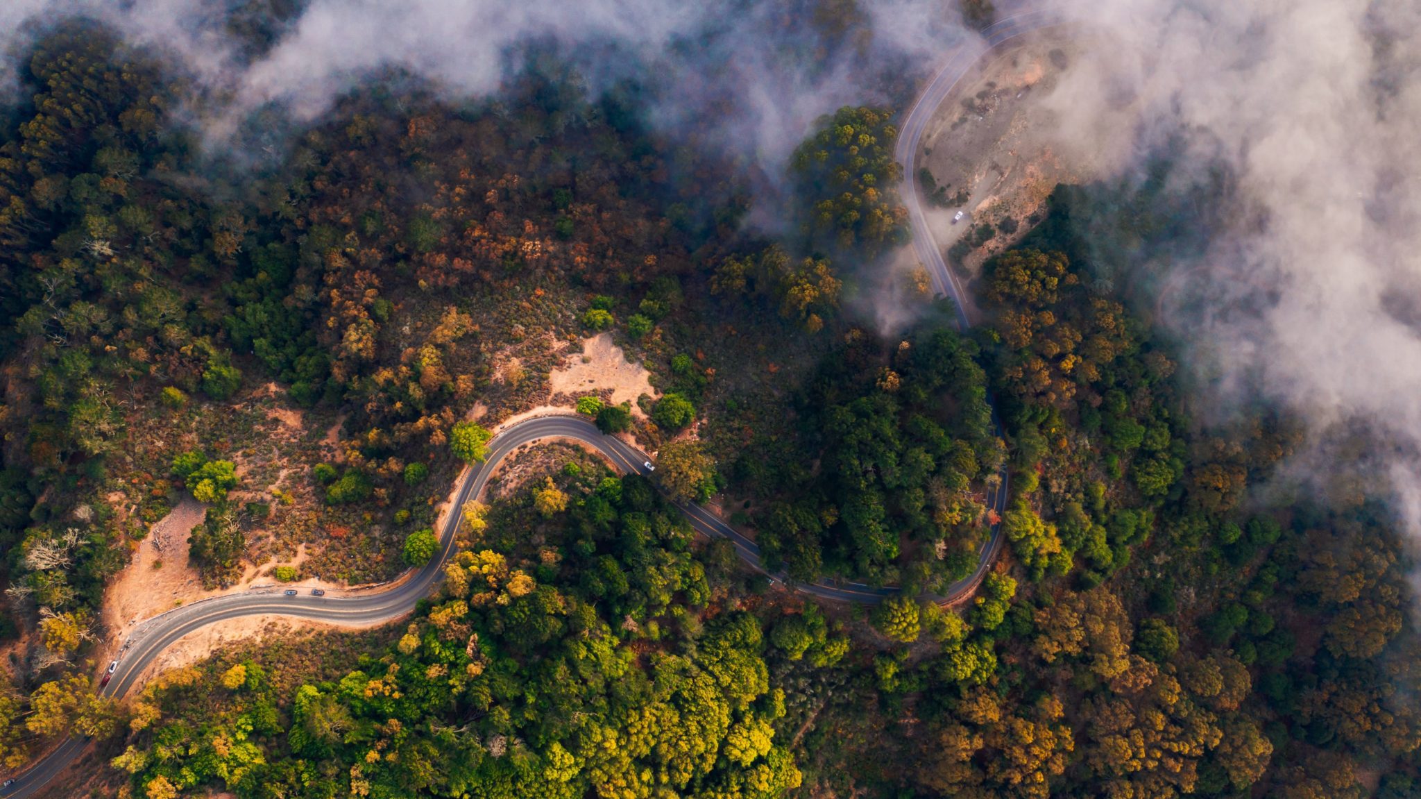 This is a bird's eye view photo of a winding road with cars on it.