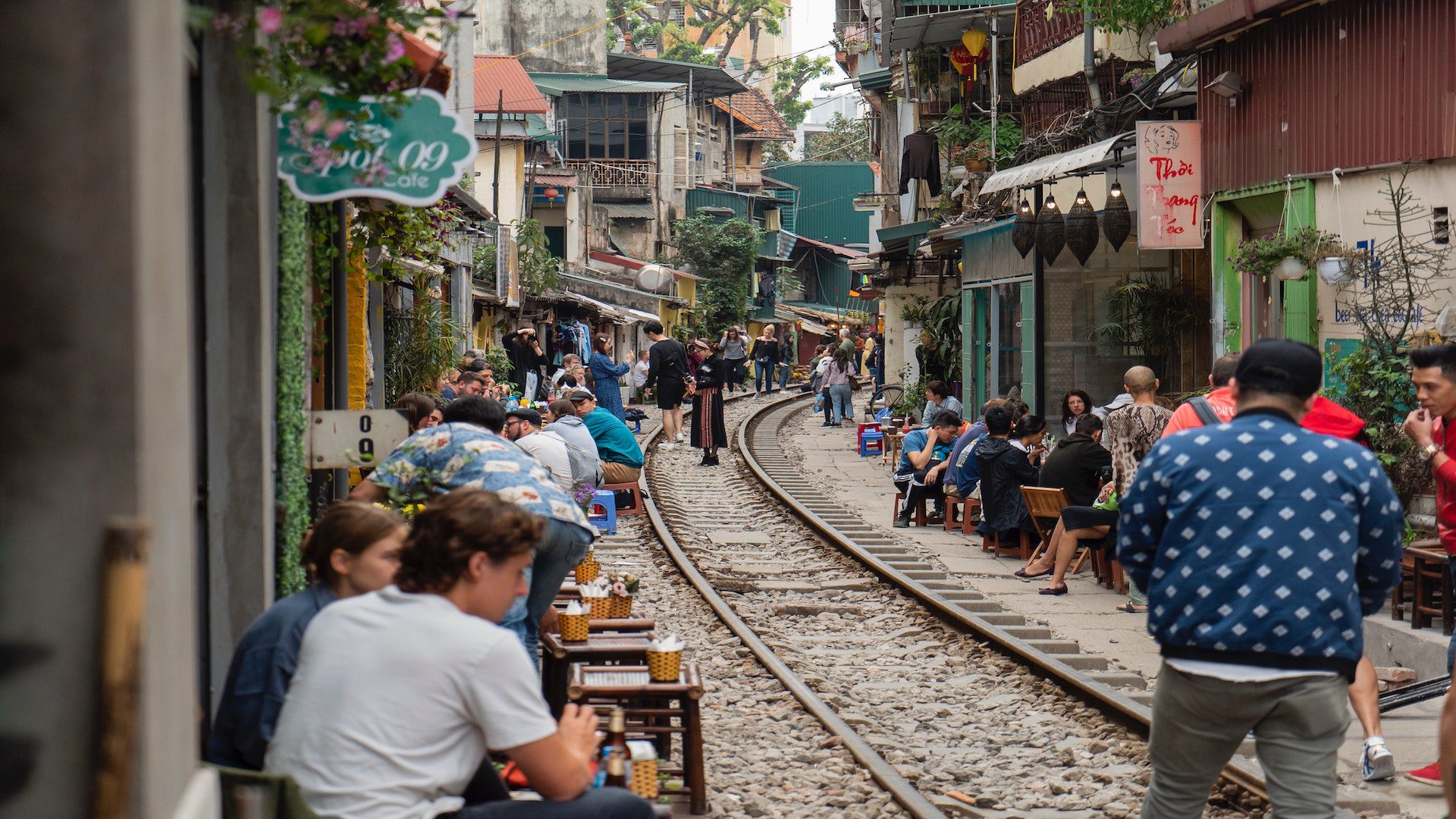 Train track that runs through a Vitanmese city – there are also cafes on each side of the track with people eating.