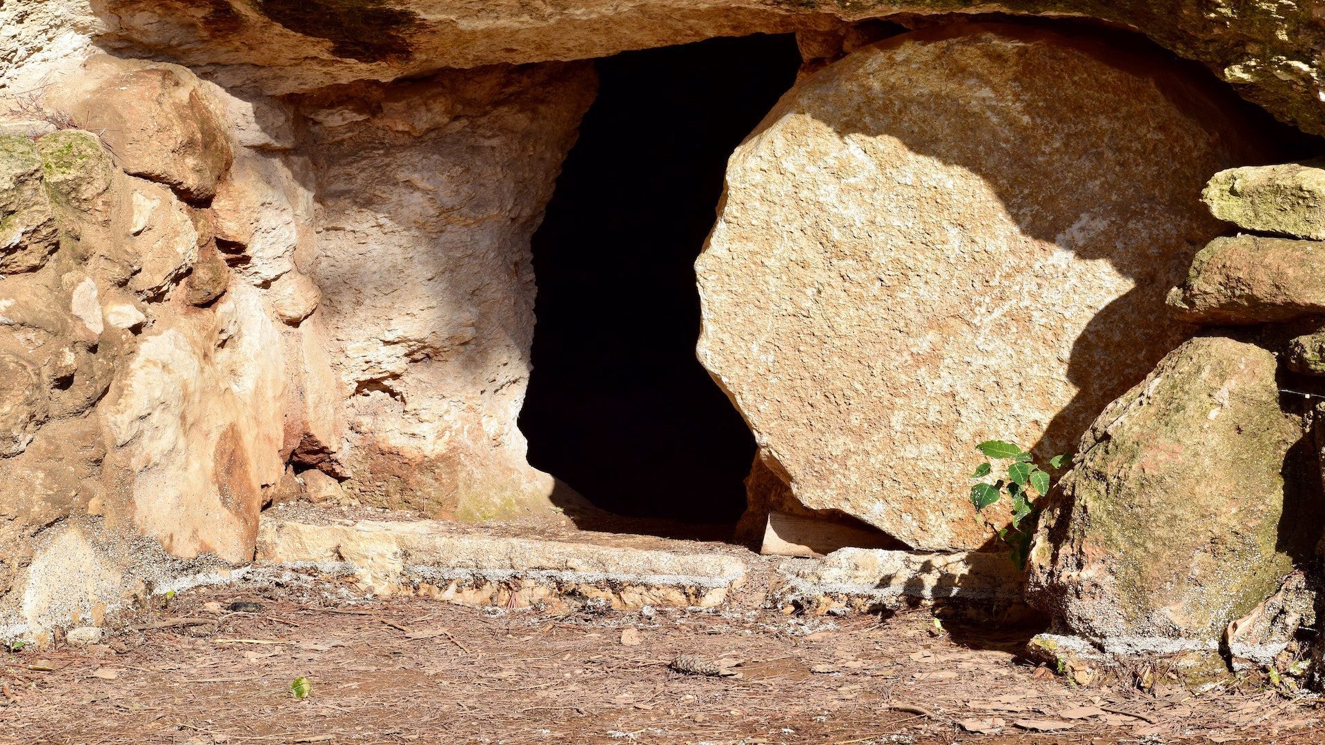 A sandstone cave that has an opening where a boulder once sat to block anyone from entering.