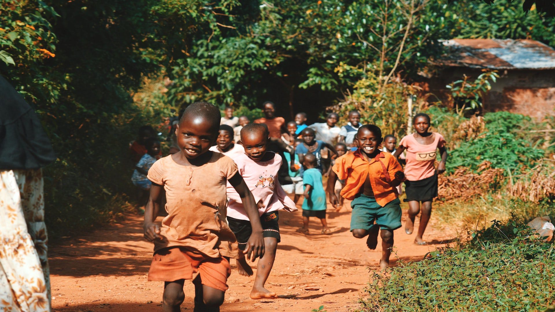 A group of children are running towards the camera and smiling.