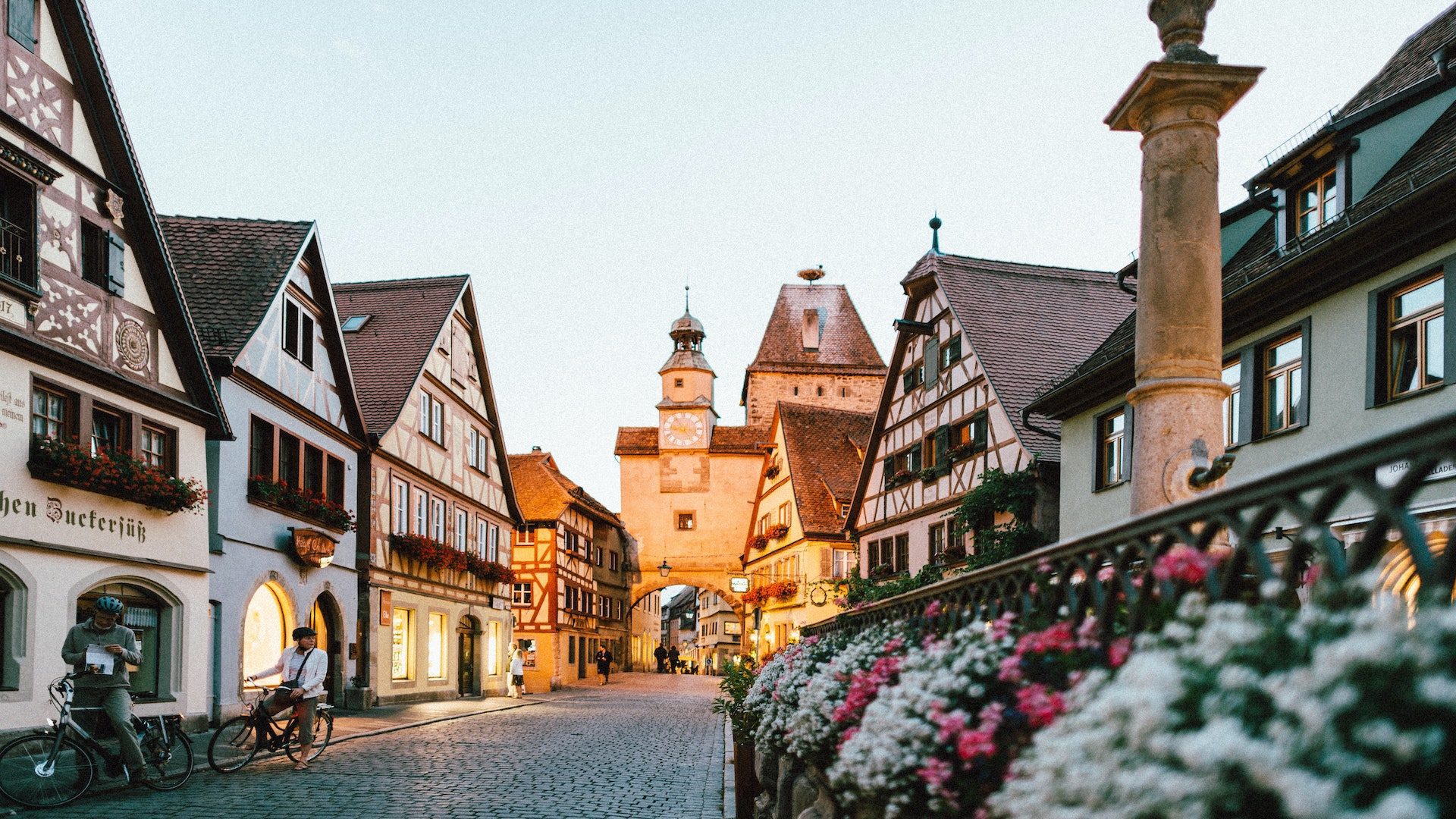 A European street with bikes on the left side and flowers on the right side at dusk.