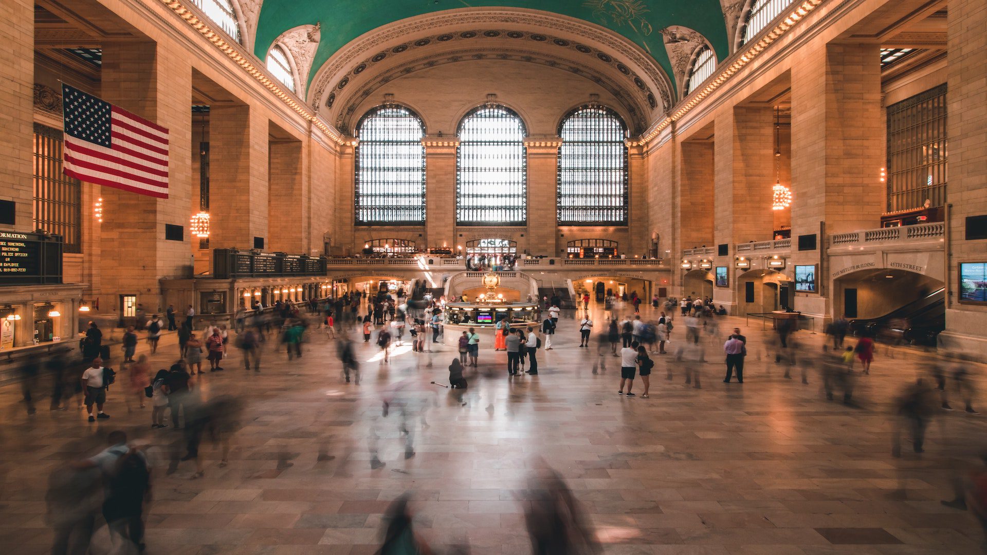 A group of people are standing and walking in Grand Central Station.