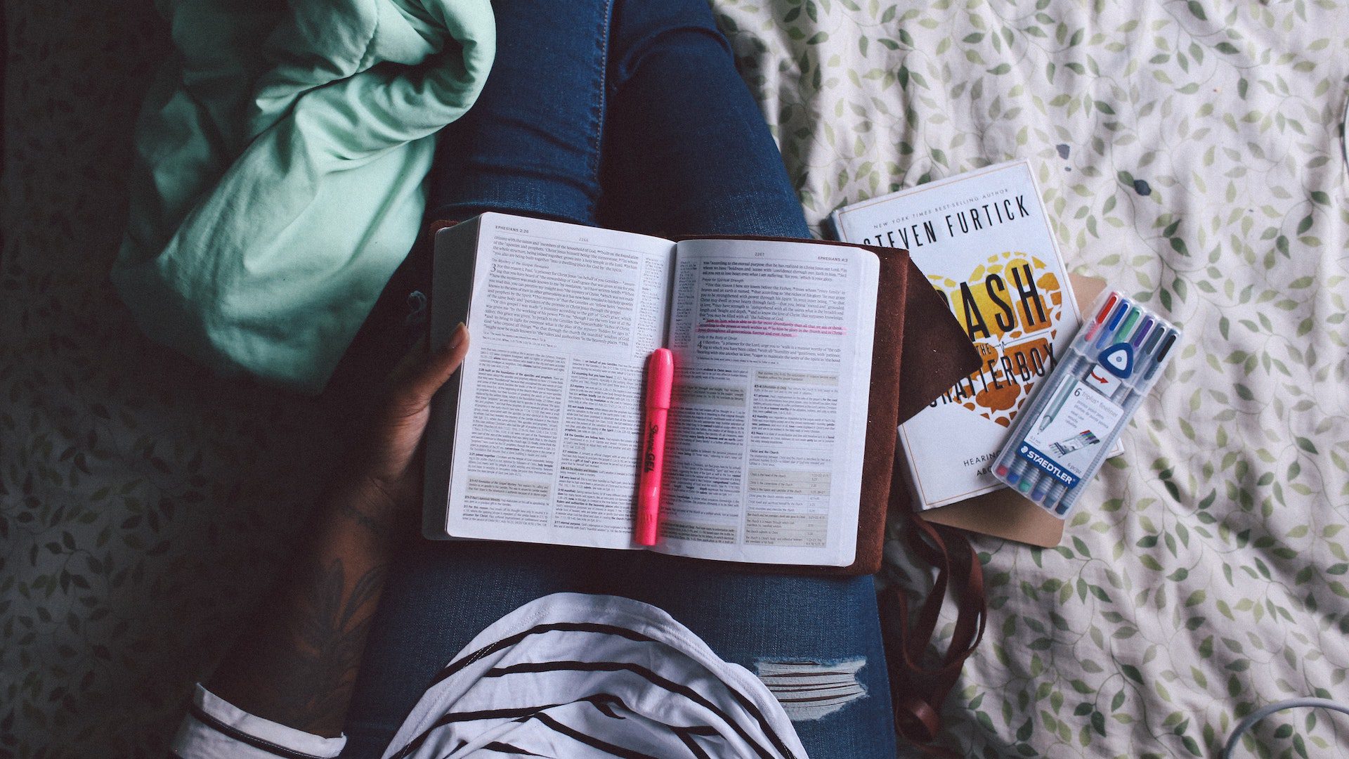 A person is holding an open Bible in their lap.