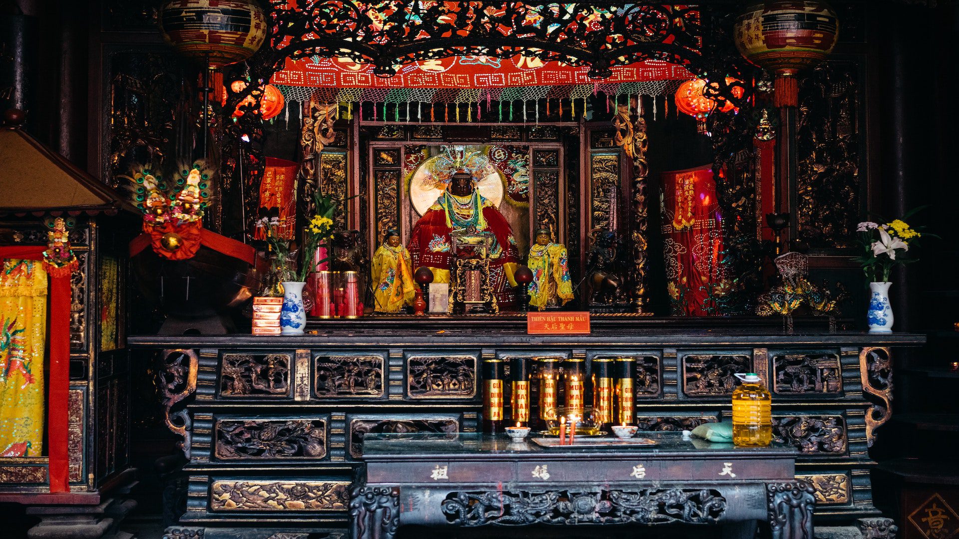 A black wooden alter with ornate detailing has a group of idols on top.