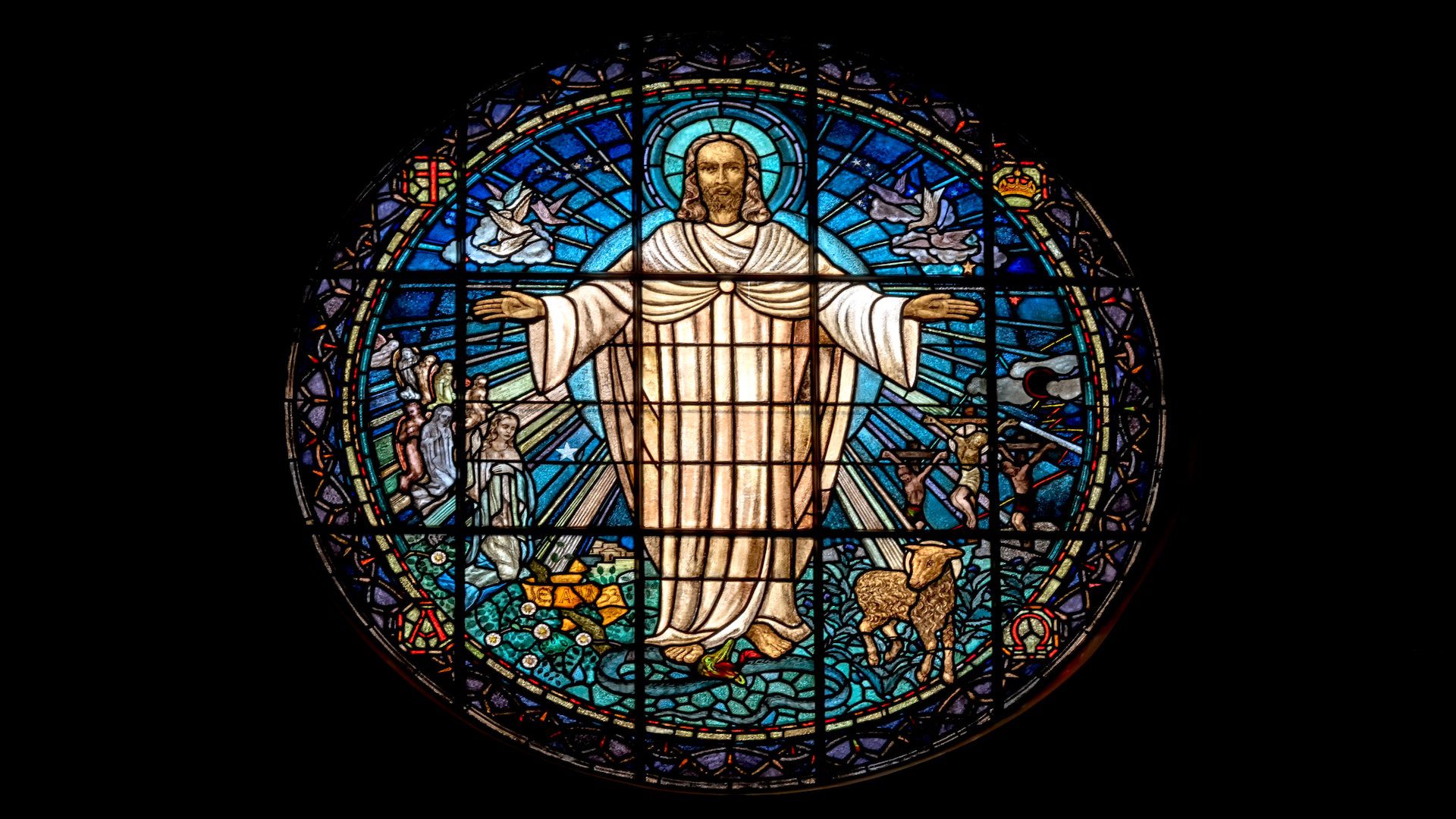 Jesus Chirst is depicted in a white robe an a halo in a beautiful stained glass scene.