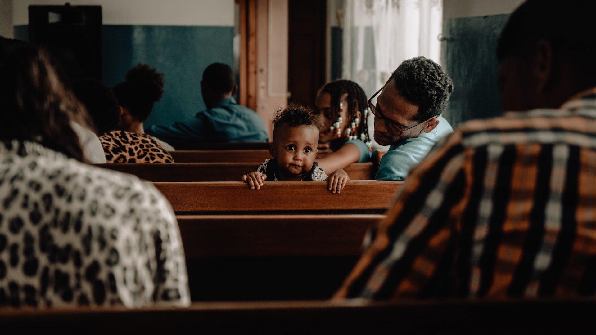 A small child sits in a church pew.