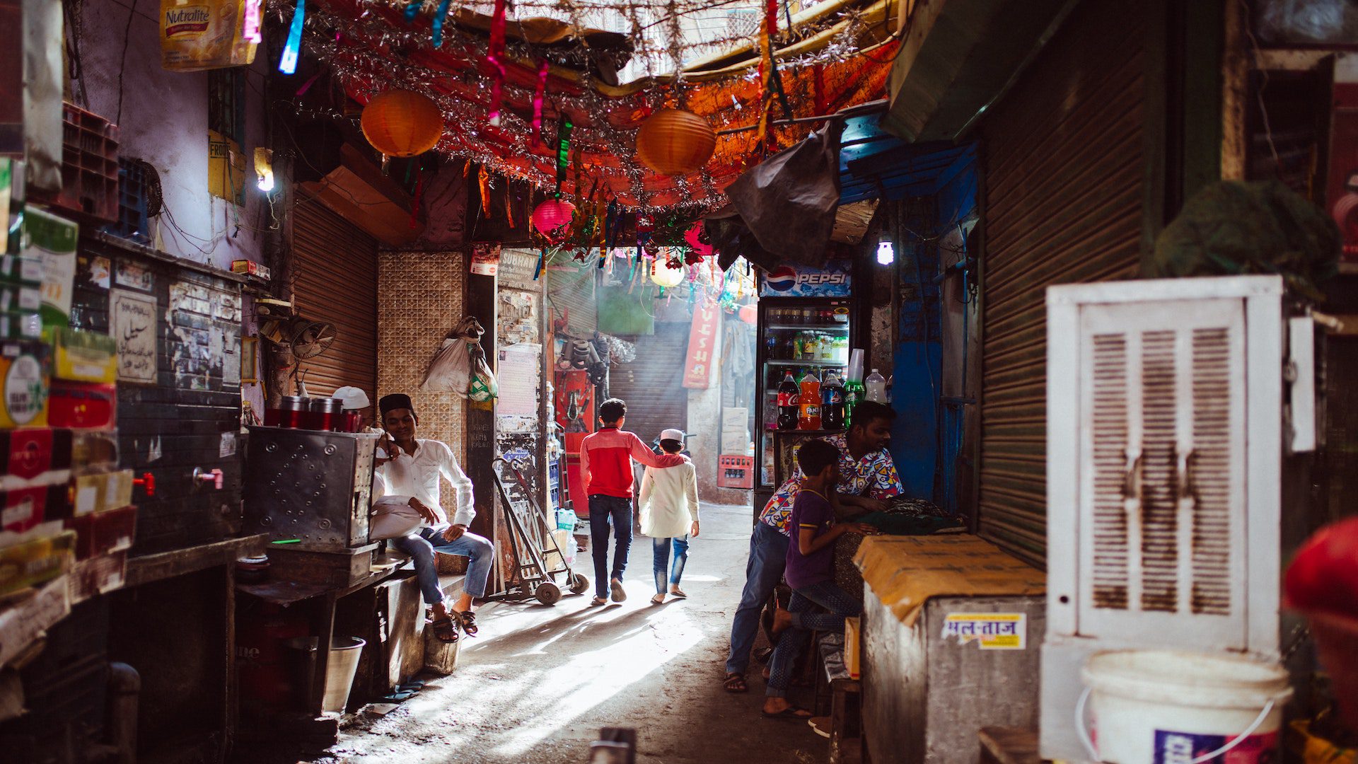A traditional market in the city of Delhi, India. The sun is shinning through the broken roof of the market.
