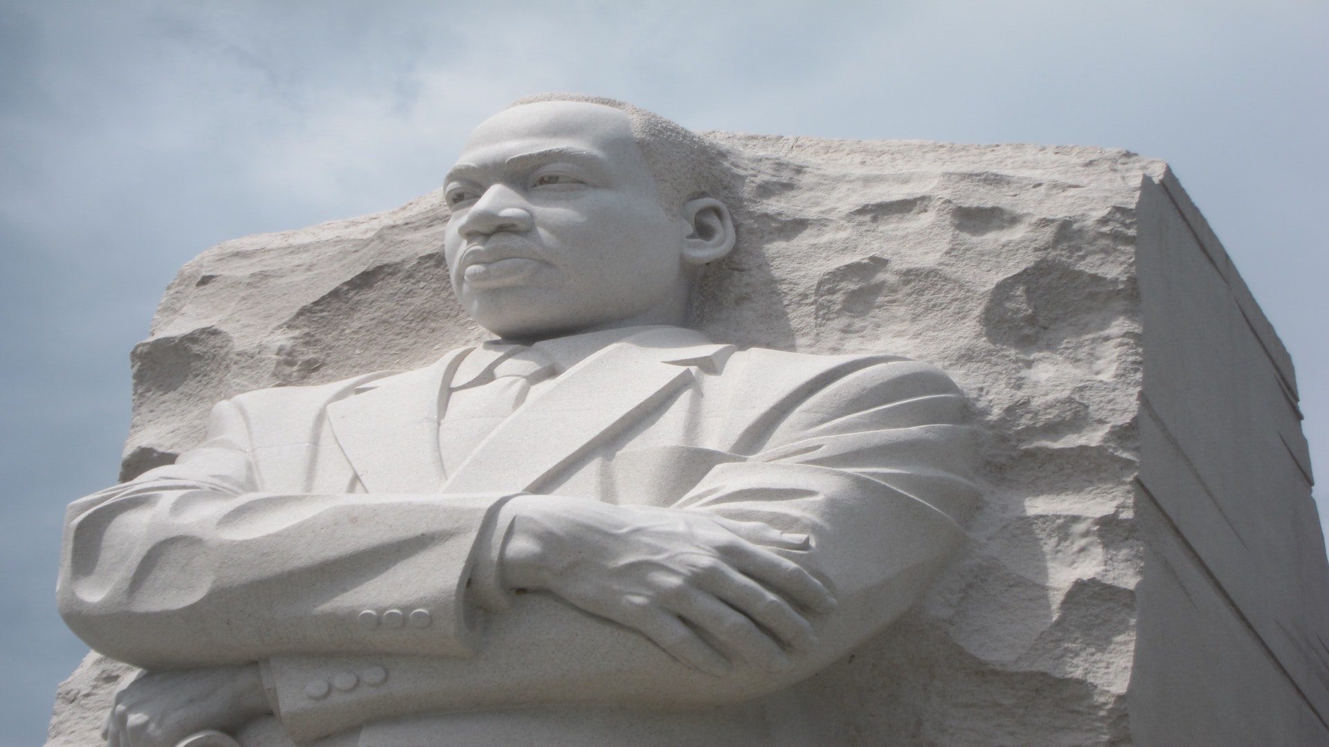 Dr. Martin Luther King Junior is represented in a limestone statue – he is wearing a suit and has his arms crossed as he looks at the view in the distance.