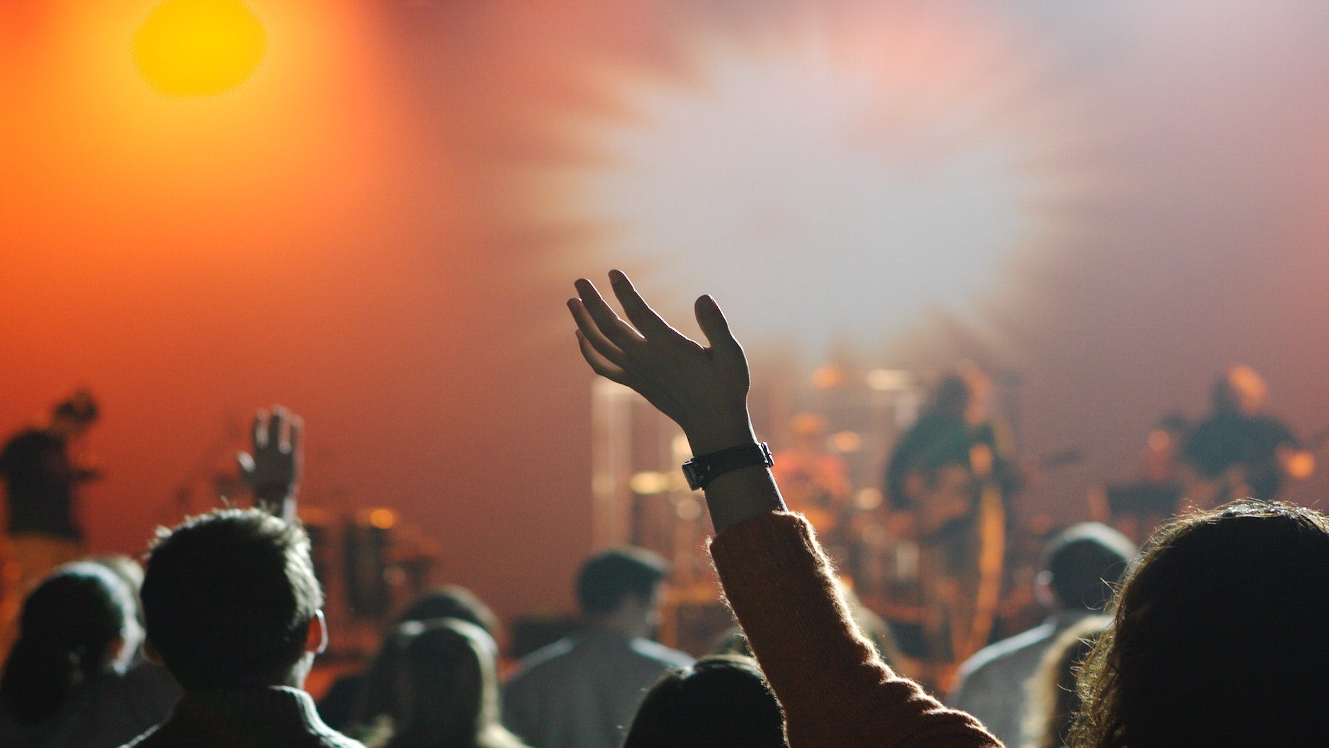 A crowd of people with their hands in the air during a church worship service.