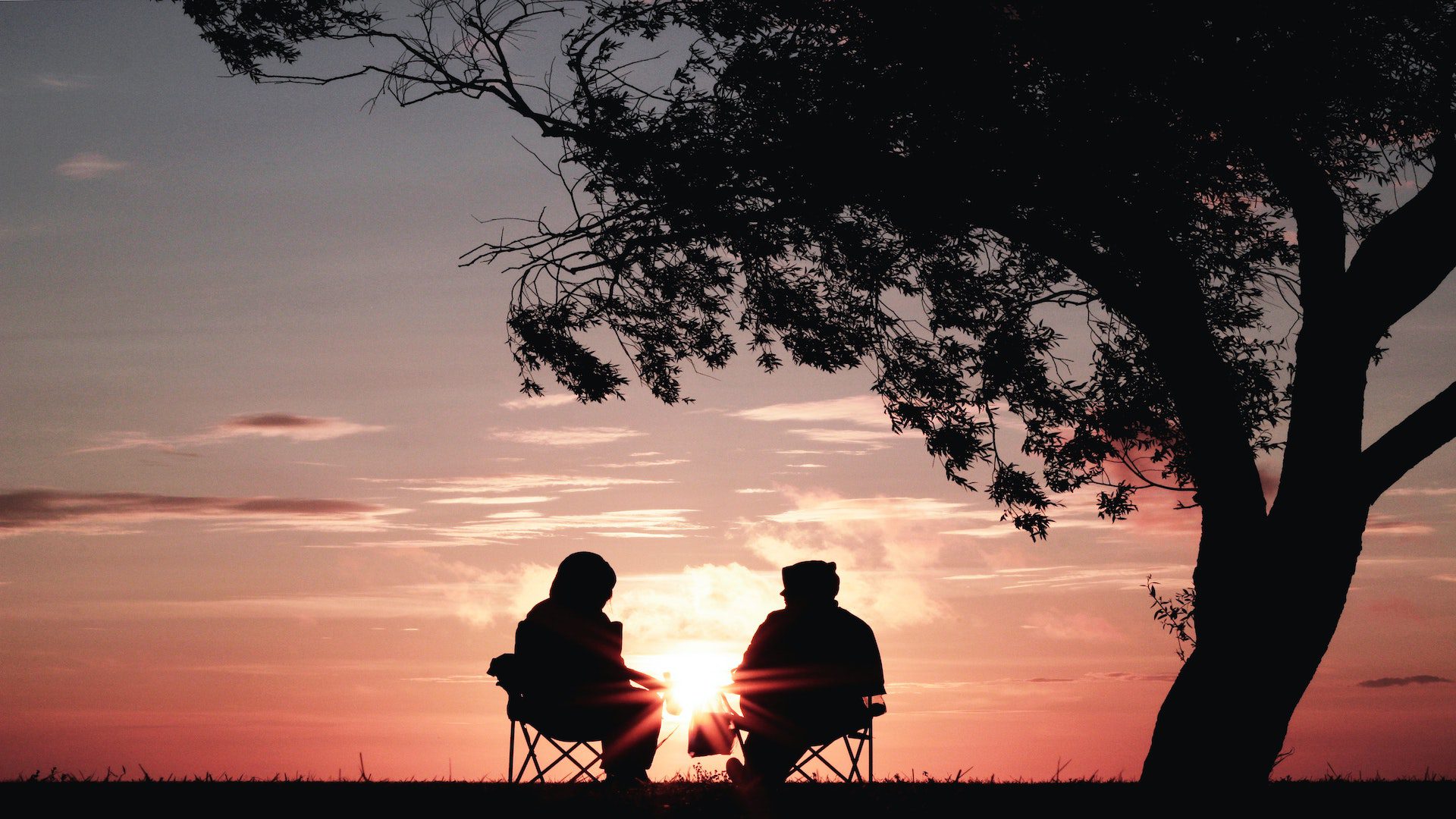 Silhouette of a two people sitting in chairs locking out at the sunset.