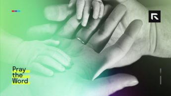 A child places their hand in their fathers hands.