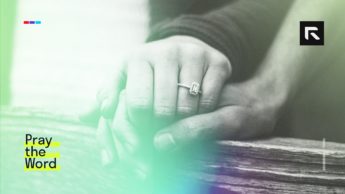 A married man and woman stand up and hold hands together.