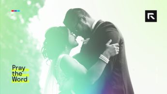 A husband and a wife stand together and look into each others eyes.