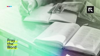 A man sits at a table and studies the Bible while journaling.
