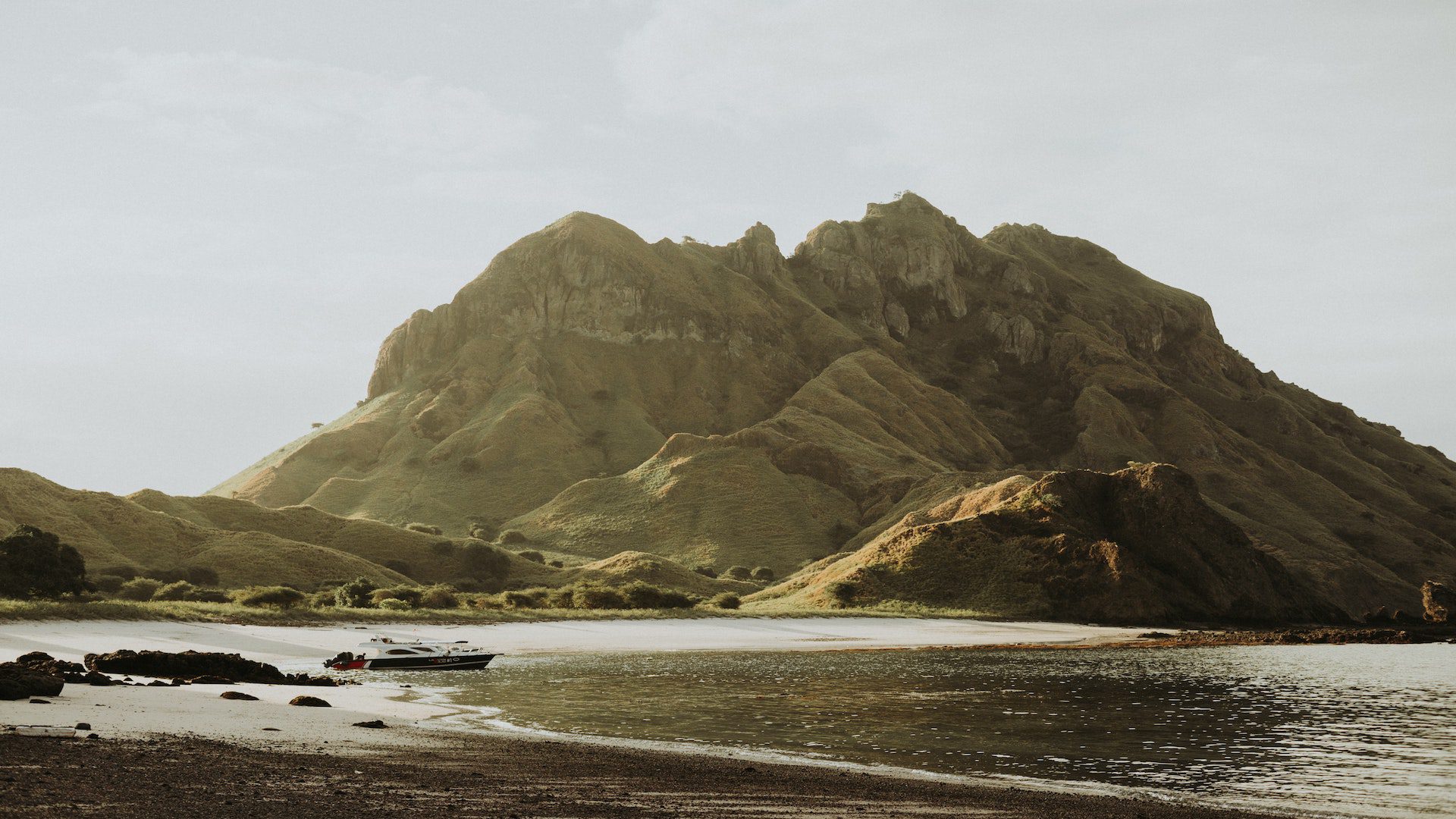 Boat in water next to green mountains.