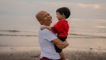 Man holding a young boy in front of the ocean.