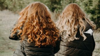 Backs of two women in black coats walking outside.