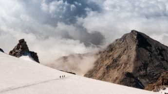 Three people walking on a snowy mountain.