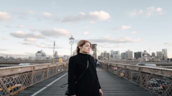 Woman standing on a bridge near a city.