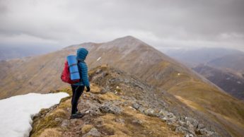 Back of a person with a backpack on a mountain with snow.