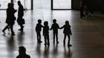 Silhouette of people walking on a concrete floor.