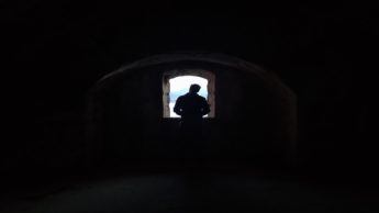 Silhouette of a man standing in front of a window in a stone tomb.