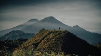 Man standing on a green mountain.
