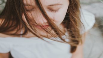 Woman in a white shirt with her eyes closed.