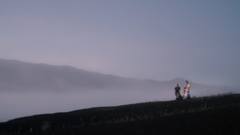 Three people on a green hill.