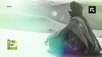 A woman sits near the sand dunes.
