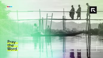 Three men walk along the river.
