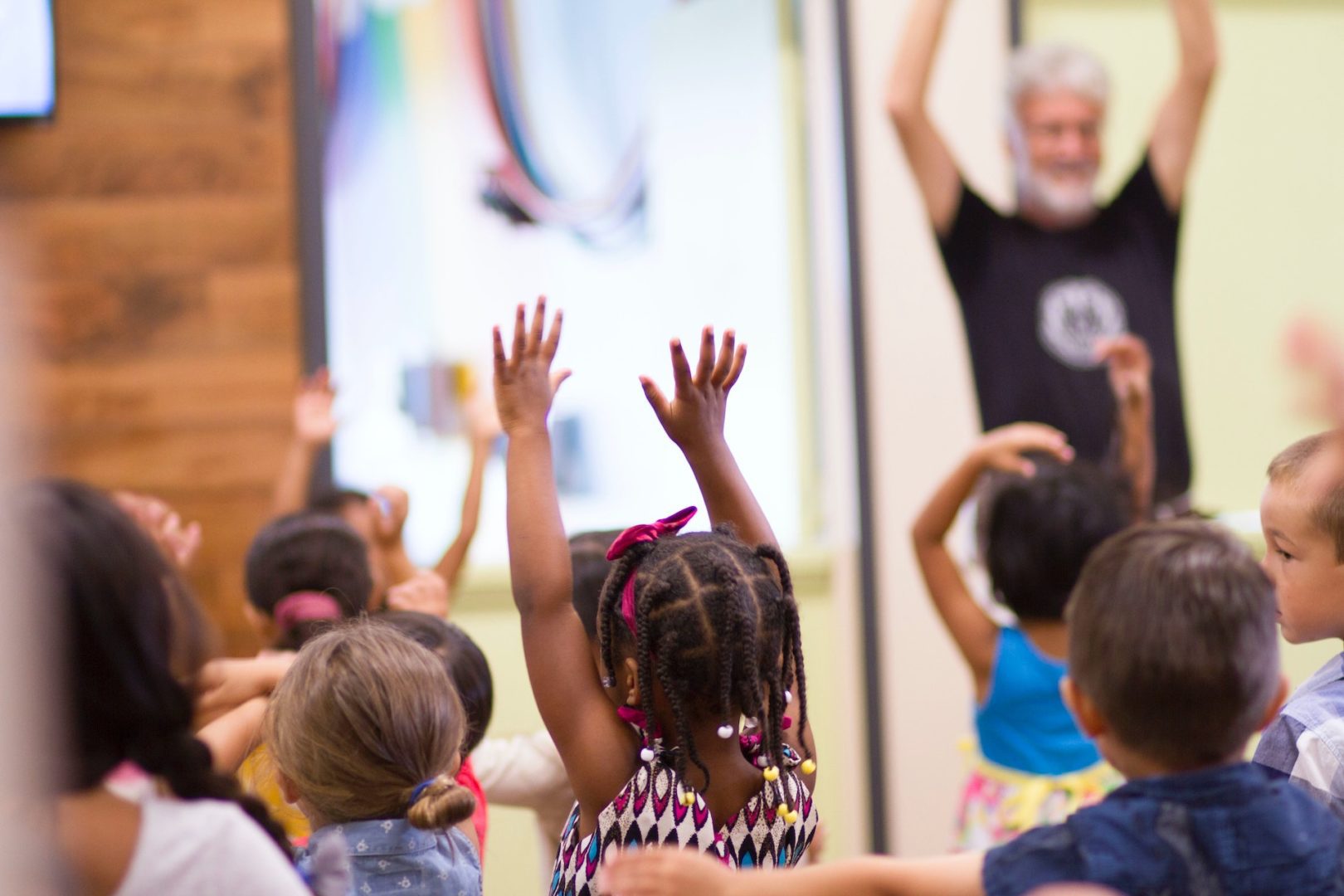 A group of children raise their hands in church.