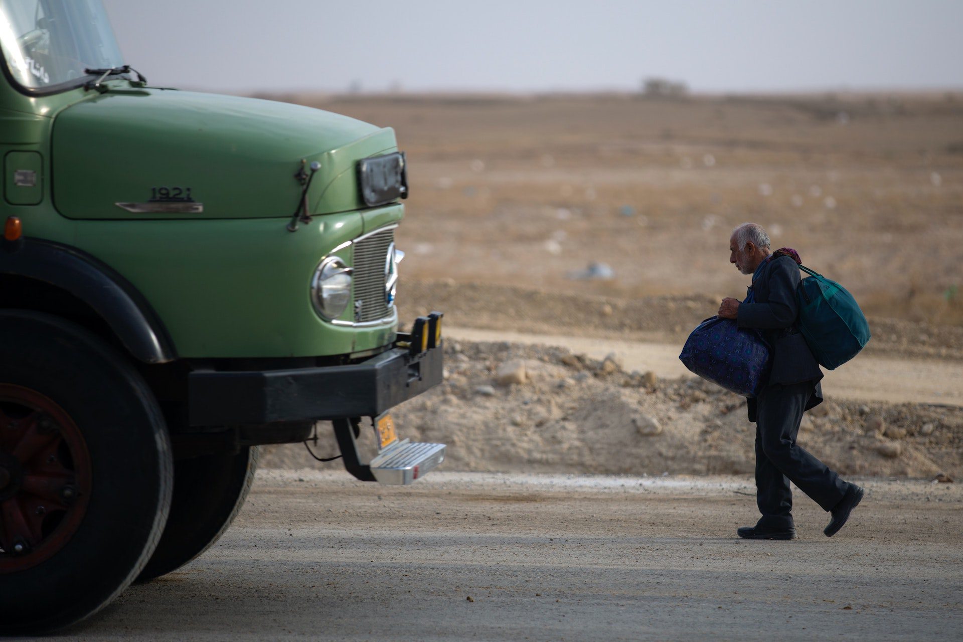 A man walks down the road in front of a green truck in Lebanon.