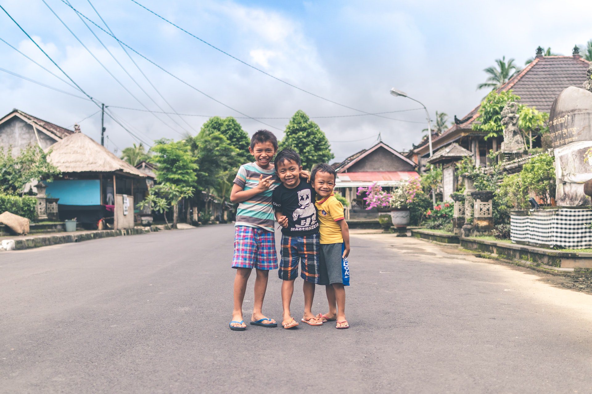 Three boys stand in the road in Indonesia.