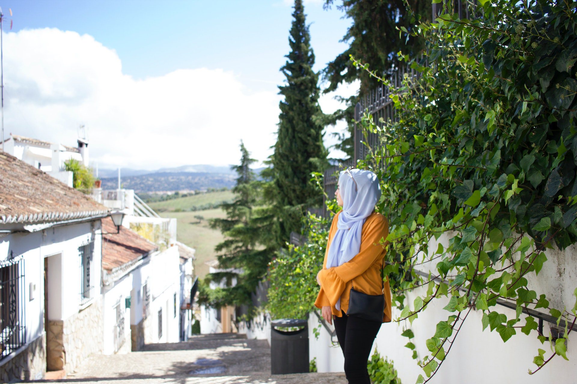 A Muslim woman stands in front of a house.