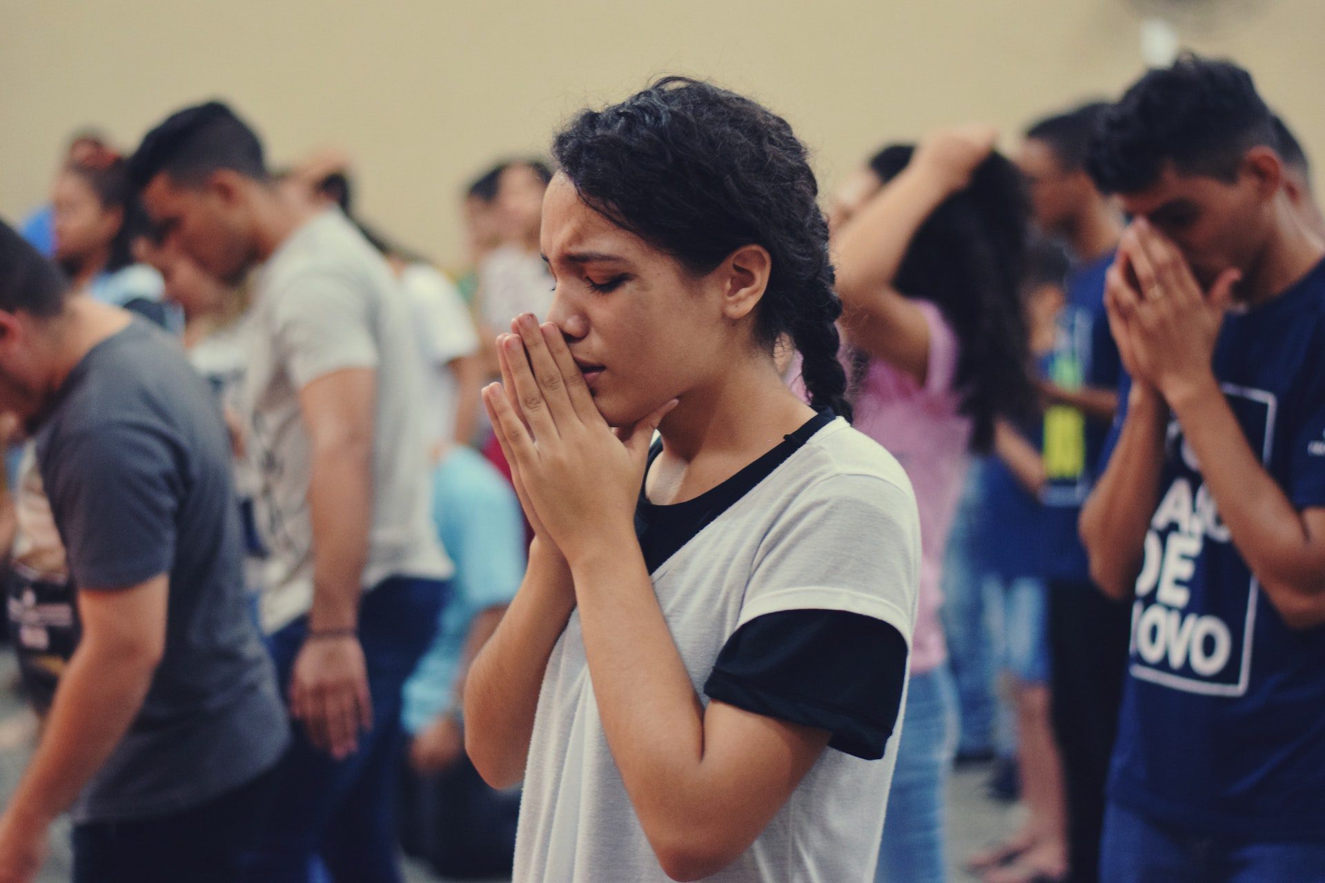A woman stands and prays in the congregation.