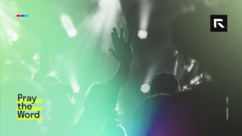 A woman raises her hand in worship to the Lord.