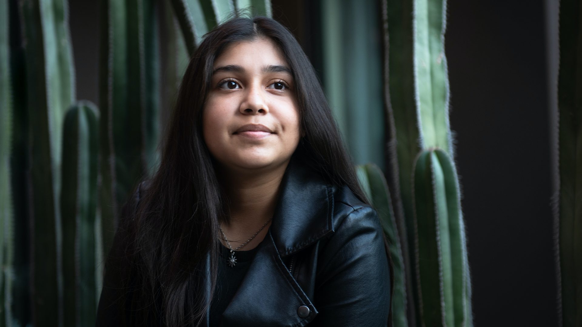 Young woman in a leather jacket in front of cactus