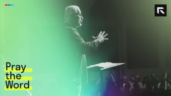Man standing on a stage behind a podium preaching