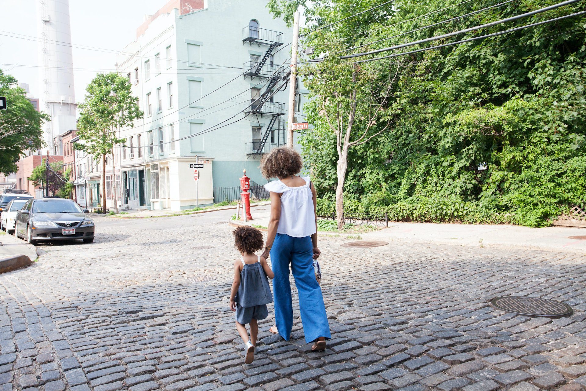A woman walks with her third culture kid in the street.