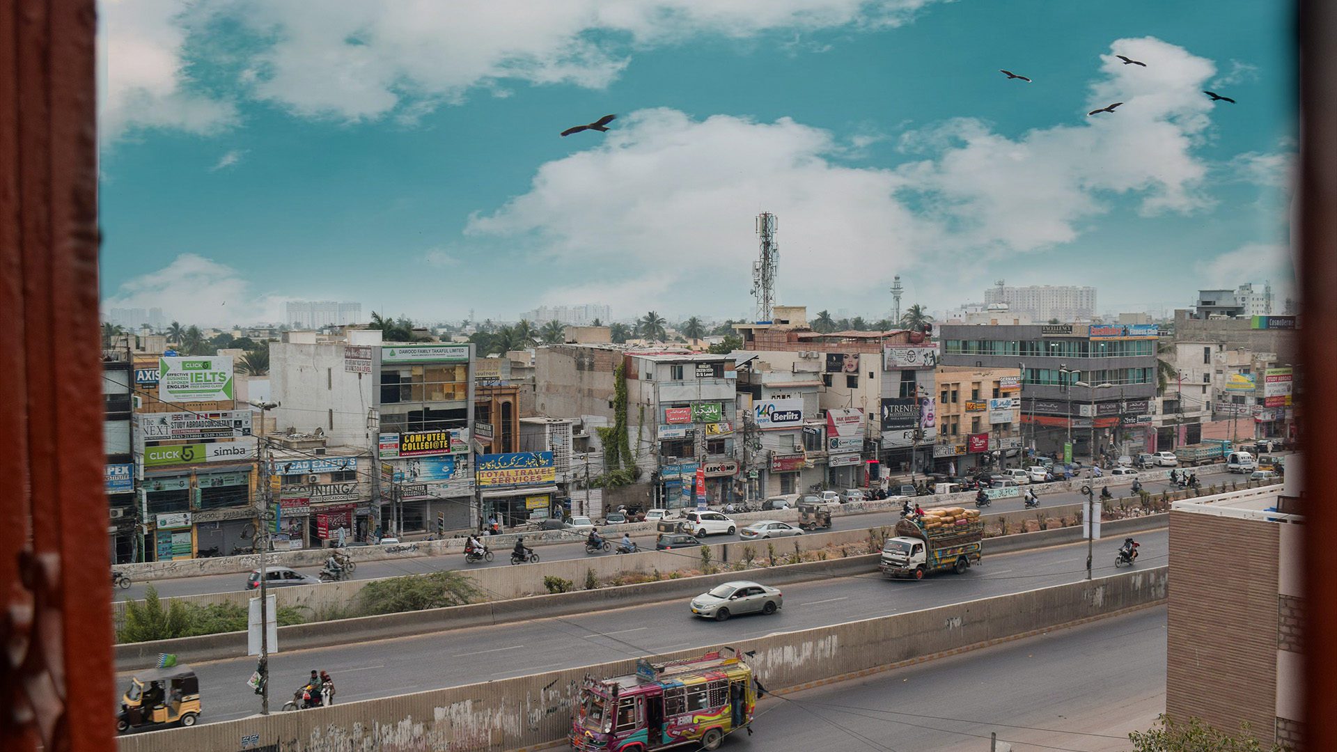 read and yellow truck on road near city during daytime in Karachi