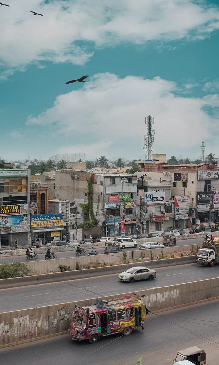 read and yellow truck on road near city during daytime in Karachi