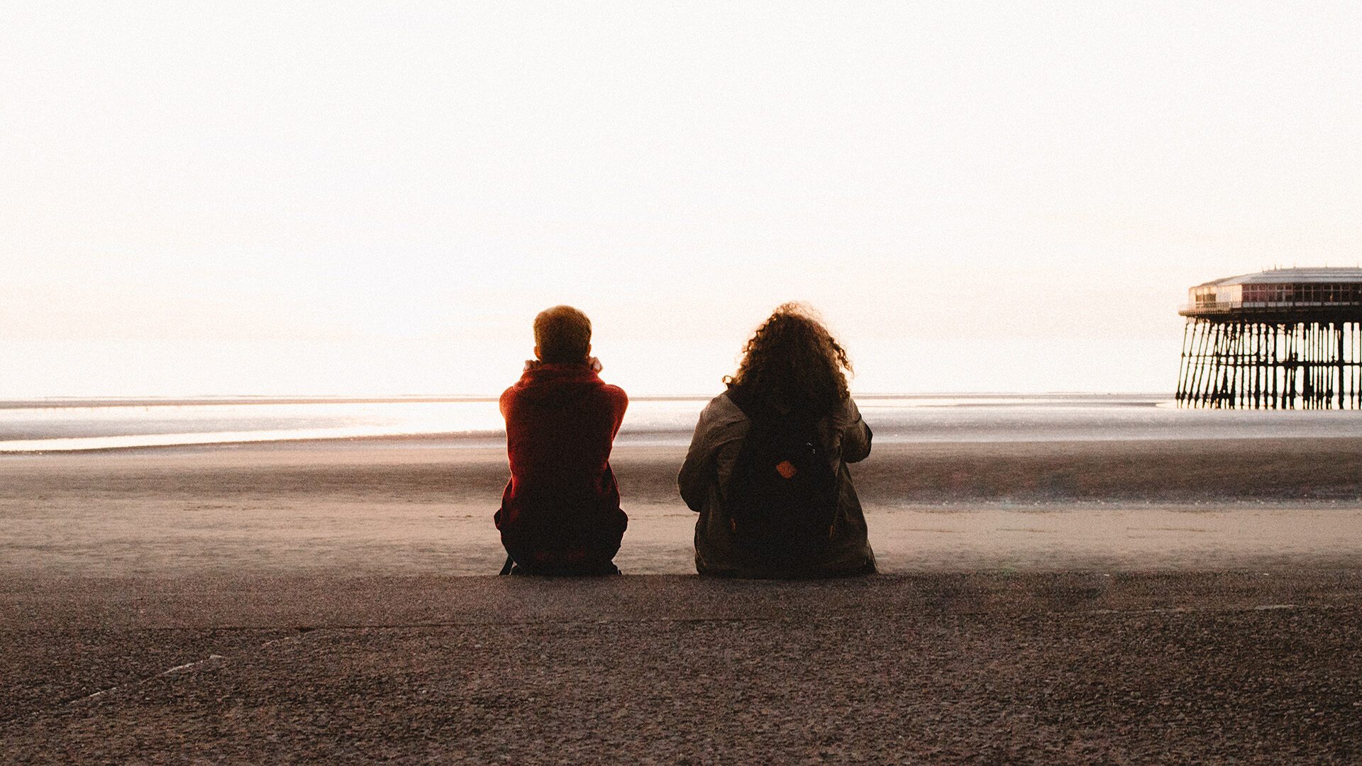 two people sitting looking at the beach