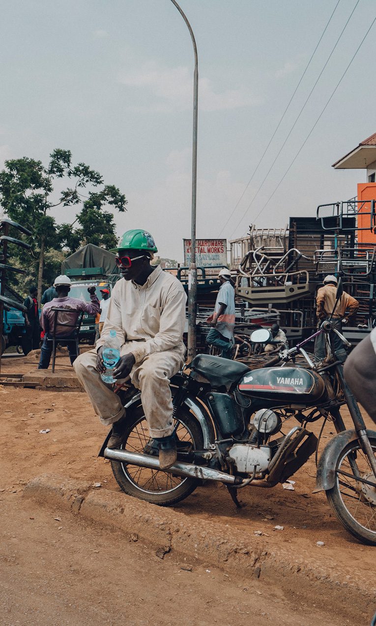 man sitting on a motorcycle near the street in an African town