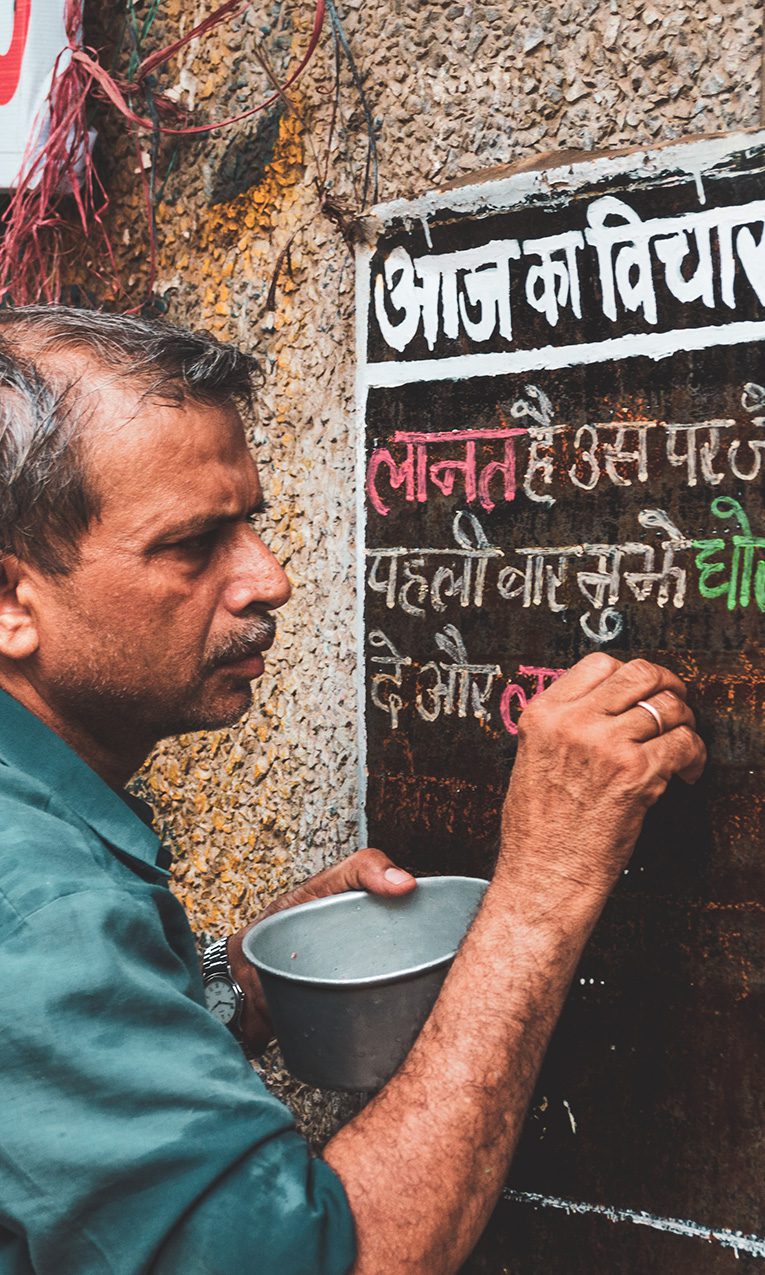 Hindu man writing in Hindi on a chalkboard