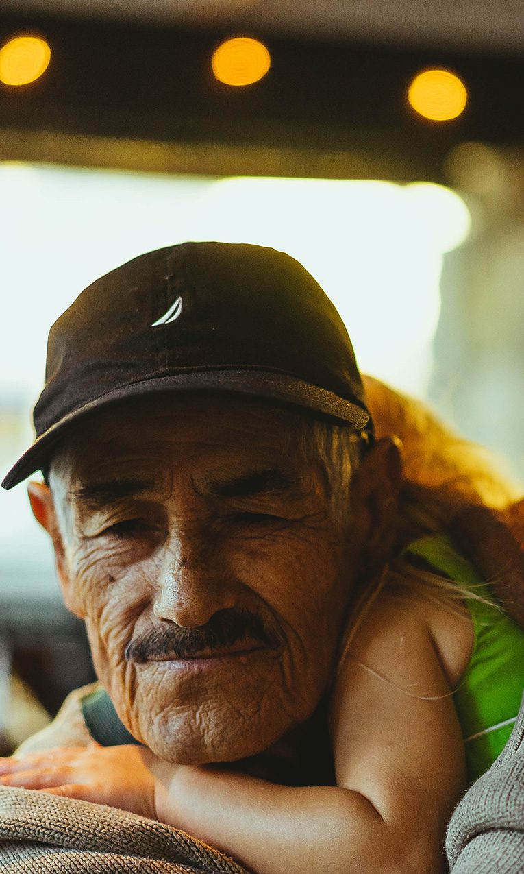 old man wearing cap carrying girl inside cafe