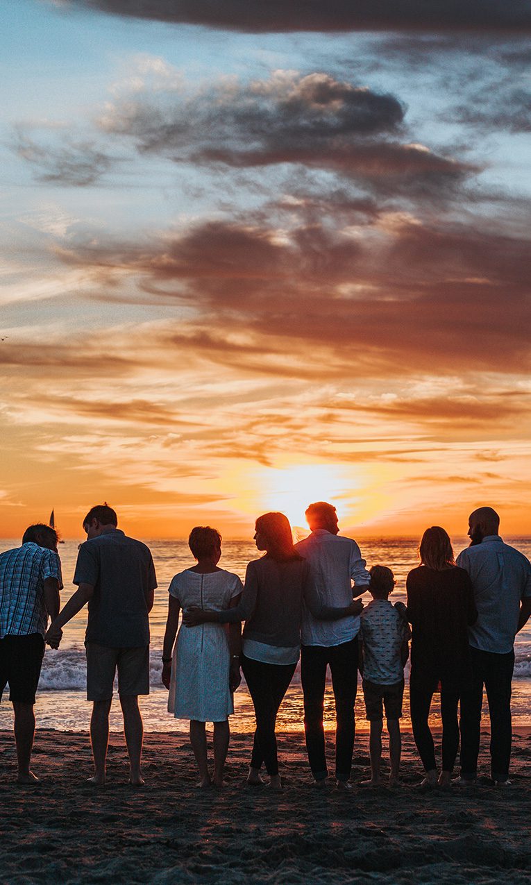 a group of people embracing on the seashore during golden hour