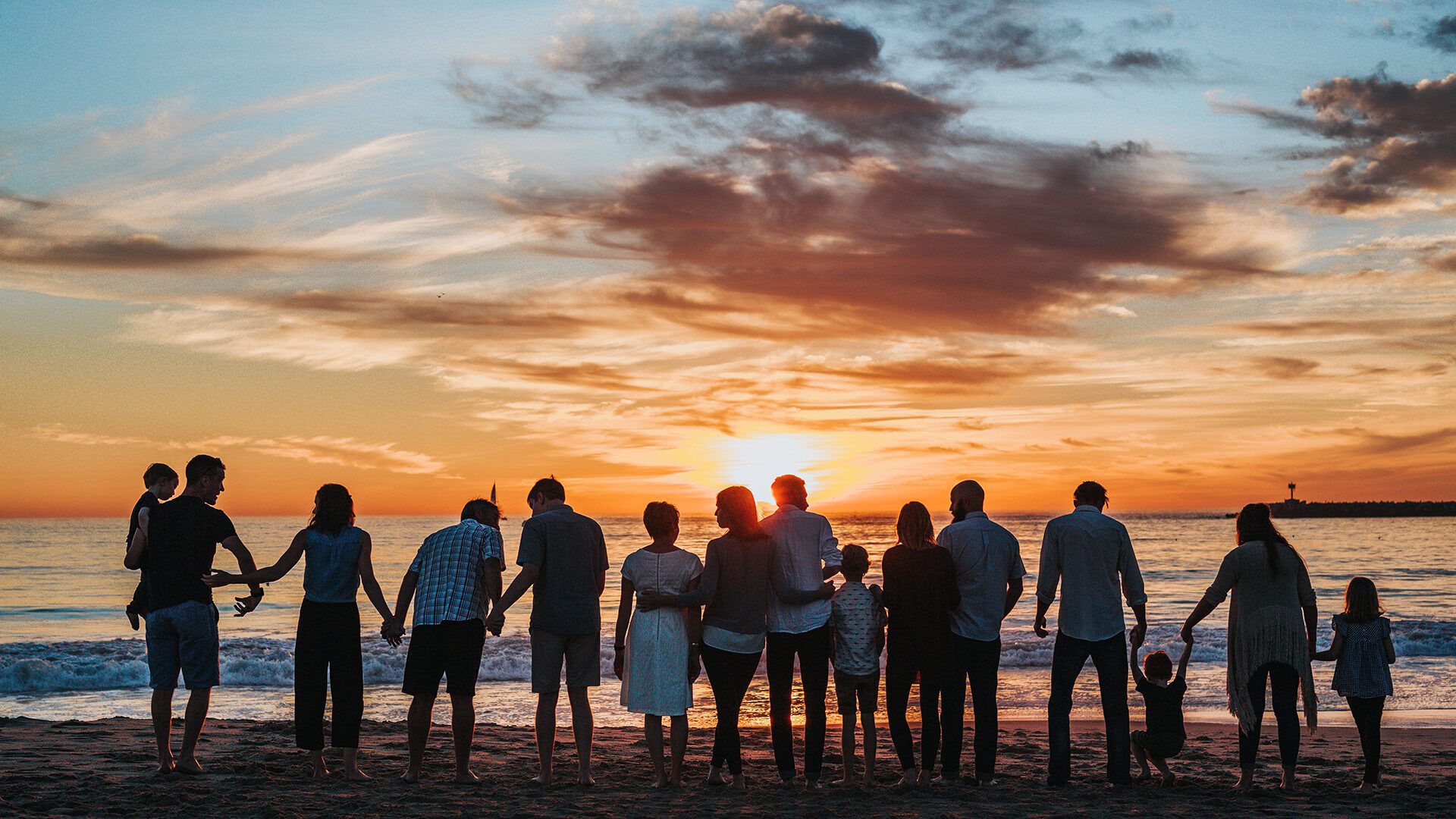 a group of people embracing on the seashore during golden hour