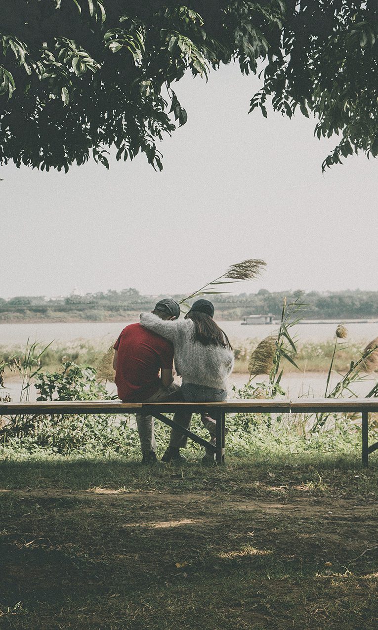 a couple hugging while sitting in a bench